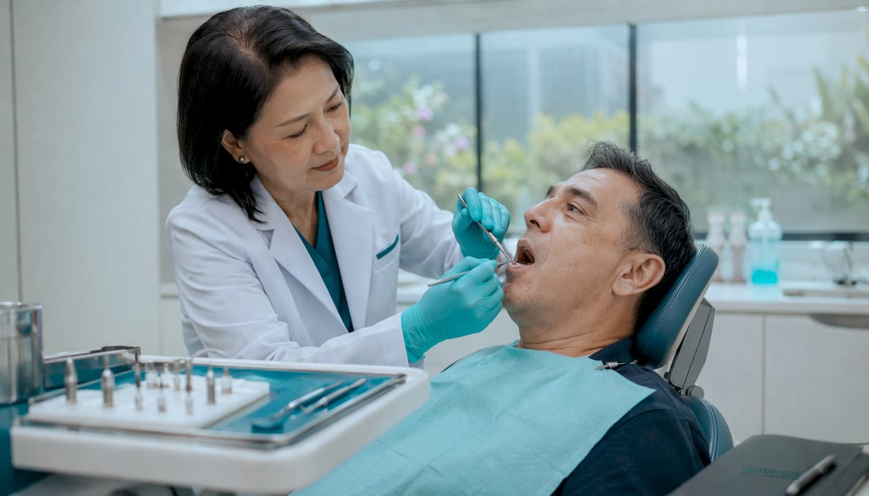 Dentist examining male patient’s gums in clinic