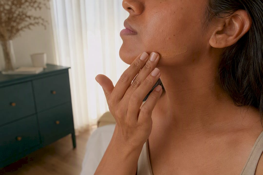 Close-up of applying tinted sunscreen to jawline